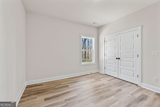 interior space with a closet, baseboards, visible vents, and light wood finished floors