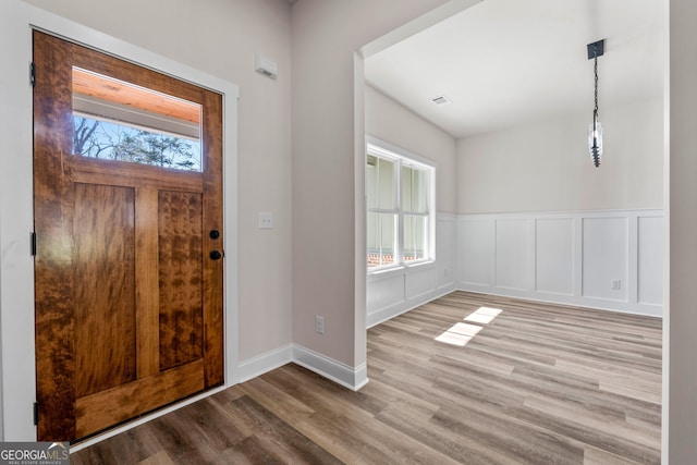 entryway with a wainscoted wall, a decorative wall, and light wood-style floors