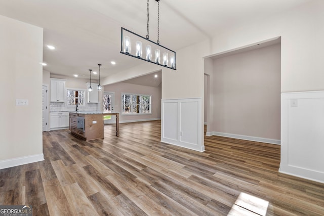 kitchen featuring light wood-style flooring, a kitchen island, white cabinetry, light countertops, and hanging light fixtures