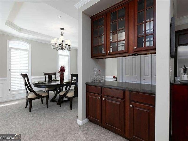 carpeted dining space featuring a chandelier, a tray ceiling, and crown molding