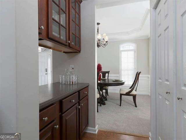 interior space featuring dark carpet, dark brown cabinetry, crown molding, and an inviting chandelier