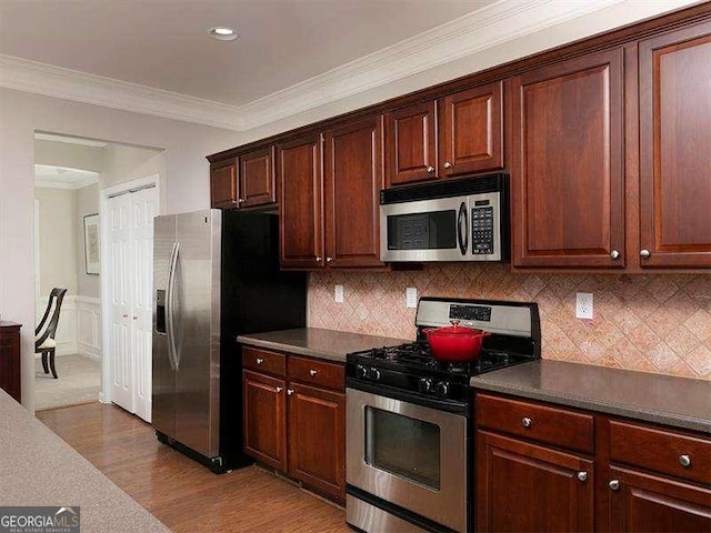 kitchen with wood-type flooring, backsplash, stainless steel appliances, and crown molding