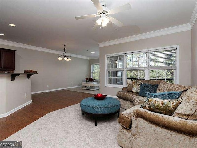 living room with ceiling fan with notable chandelier, dark hardwood / wood-style flooring, and ornamental molding