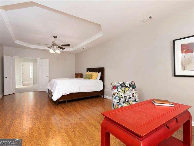 bedroom featuring wood-type flooring, a tray ceiling, and ceiling fan