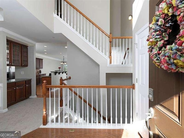 stairs with carpet, a high ceiling, and ornamental molding