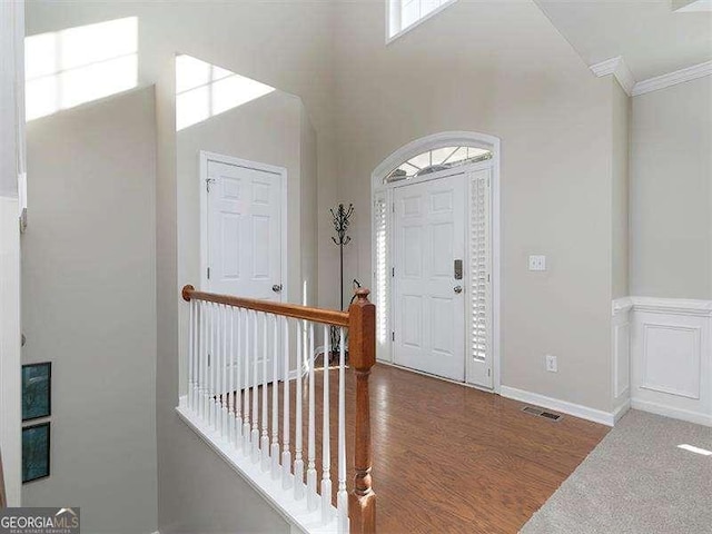 foyer with dark hardwood / wood-style flooring, crown molding, and a high ceiling