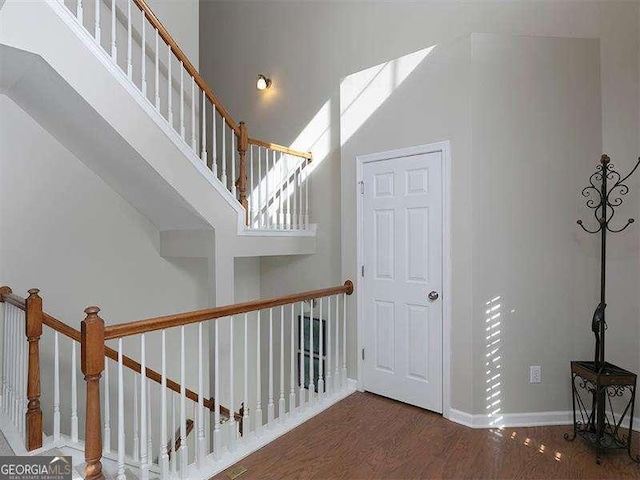 stairway with a towering ceiling and hardwood / wood-style flooring