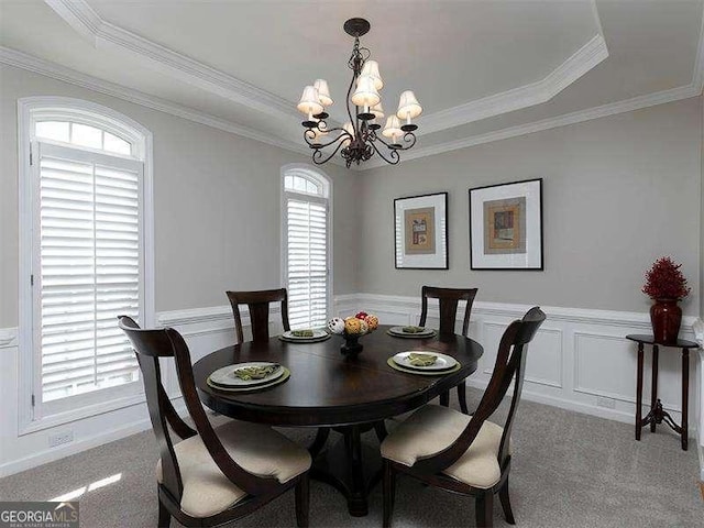 dining room featuring a raised ceiling, crown molding, light colored carpet, and a notable chandelier