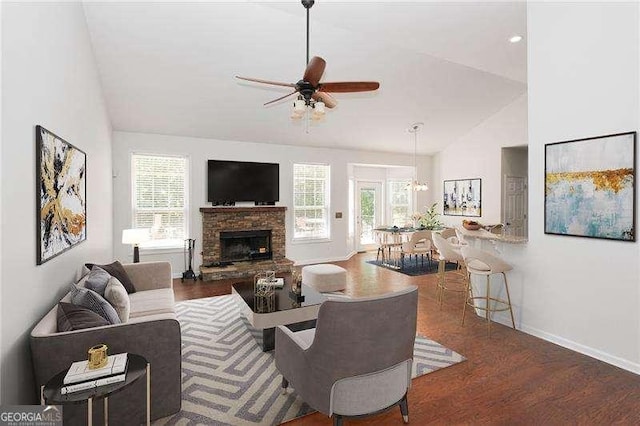 living room with a fireplace, high vaulted ceiling, dark wood-type flooring, and ceiling fan with notable chandelier