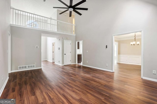 unfurnished living room featuring a high ceiling, ceiling fan with notable chandelier, and dark hardwood / wood-style floors