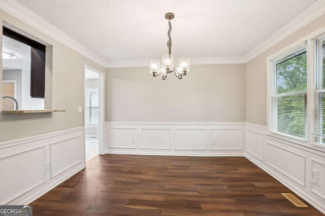 unfurnished dining area featuring ornamental molding, dark wood-type flooring, and a notable chandelier