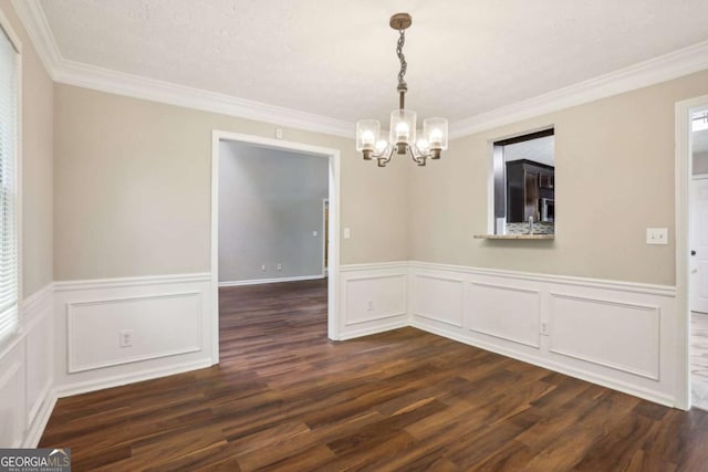 unfurnished dining area with an inviting chandelier, dark hardwood / wood-style floors, and ornamental molding