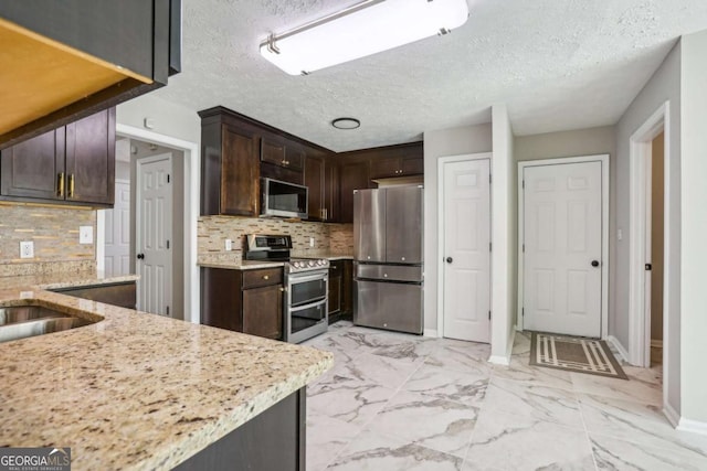 kitchen with decorative backsplash, stainless steel appliances, and light stone counters