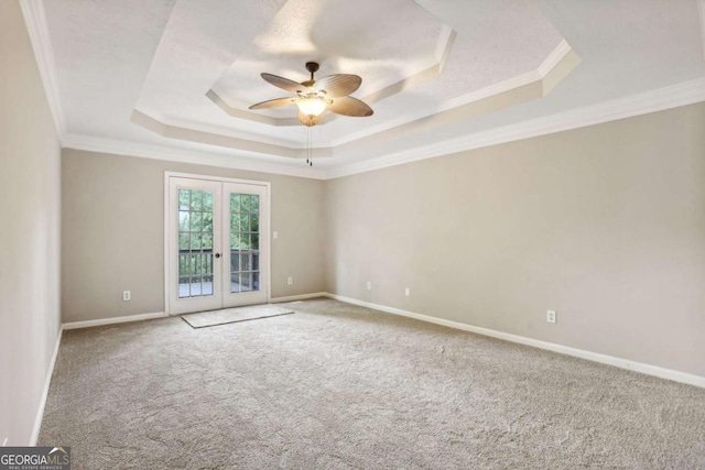 empty room featuring a raised ceiling, crown molding, french doors, and ceiling fan