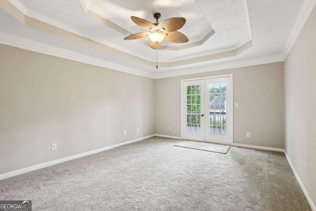 empty room featuring ceiling fan, ornamental molding, a tray ceiling, and french doors