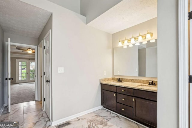 bathroom with ceiling fan, french doors, vanity, and a textured ceiling