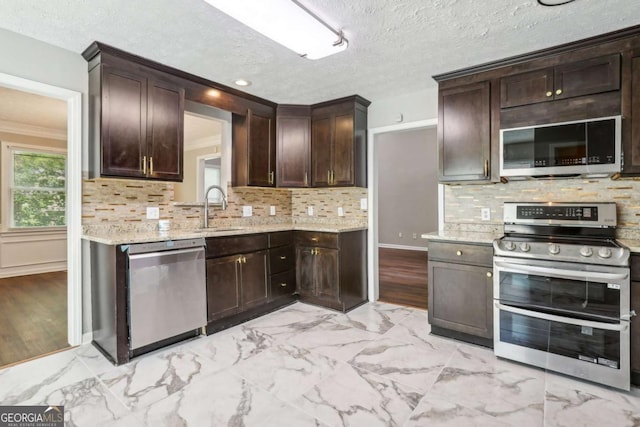 kitchen featuring appliances with stainless steel finishes, dark brown cabinetry, tasteful backsplash, and sink