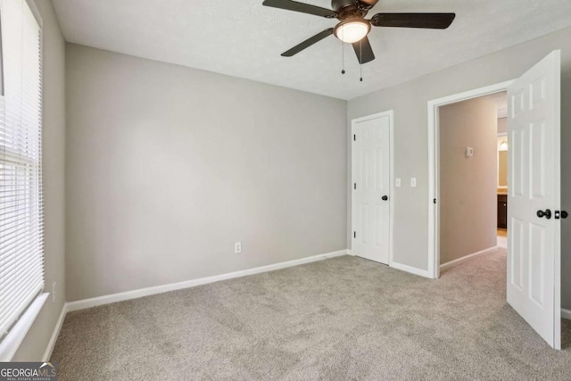 unfurnished bedroom with a closet, light colored carpet, and ceiling fan