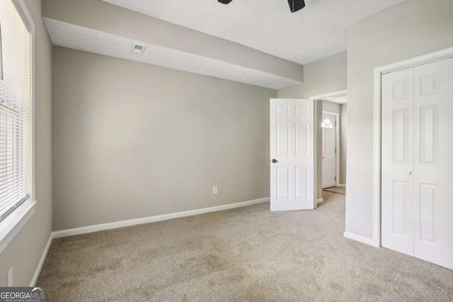 unfurnished bedroom with light carpet, a closet, and ceiling fan