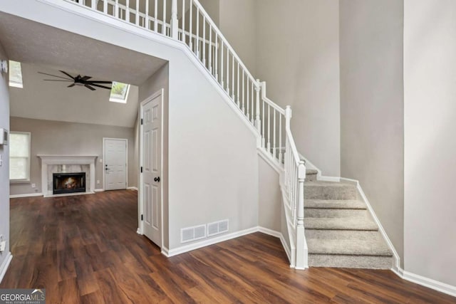 stairs with wood-type flooring, vaulted ceiling, and ceiling fan