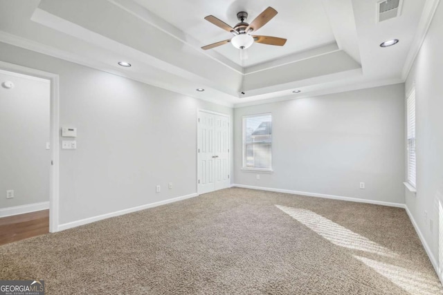 carpeted empty room featuring crown molding, ceiling fan, and a tray ceiling