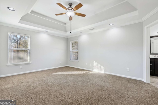 carpeted empty room with ornamental molding, a raised ceiling, and ceiling fan