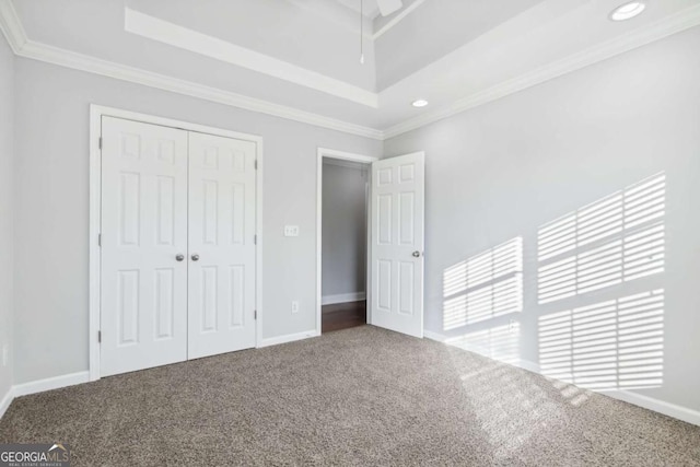 unfurnished bedroom featuring crown molding, a tray ceiling, and carpet flooring