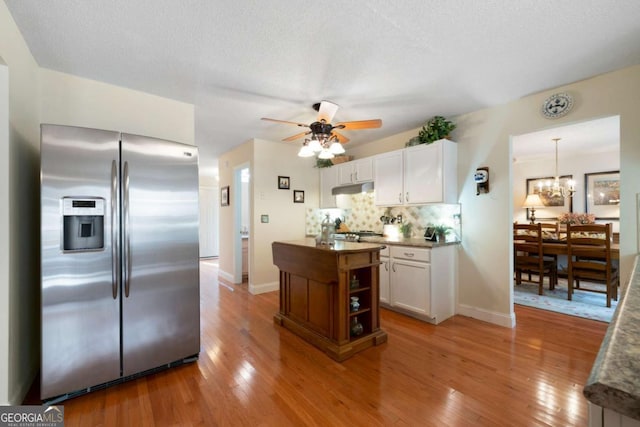 kitchen featuring stainless steel fridge, a textured ceiling, light hardwood / wood-style floors, and white cabinetry