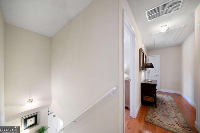 corridor featuring light wood-type flooring and a textured ceiling