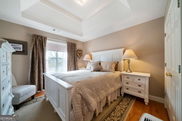 bedroom with a raised ceiling and hardwood / wood-style flooring