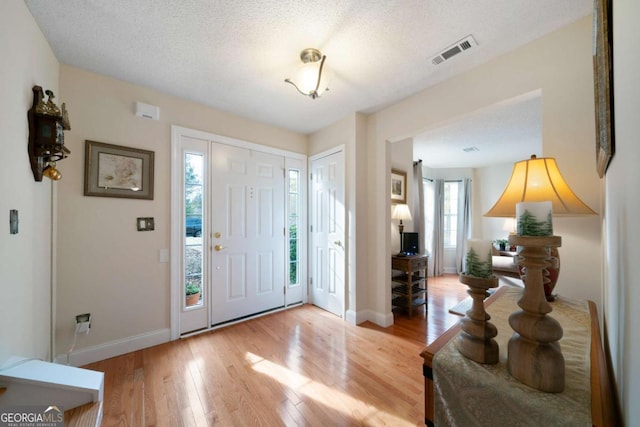 foyer entrance featuring a textured ceiling and light wood-type flooring