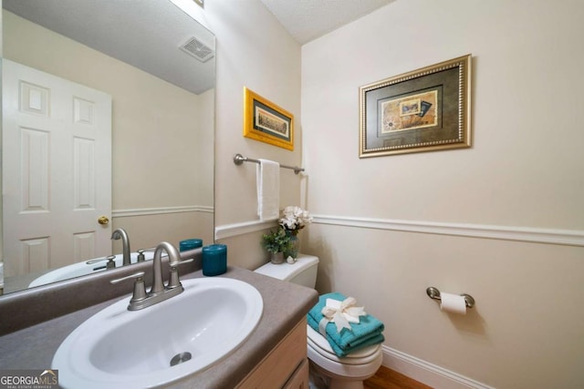 bathroom with vanity, wood-type flooring, a textured ceiling, and toilet