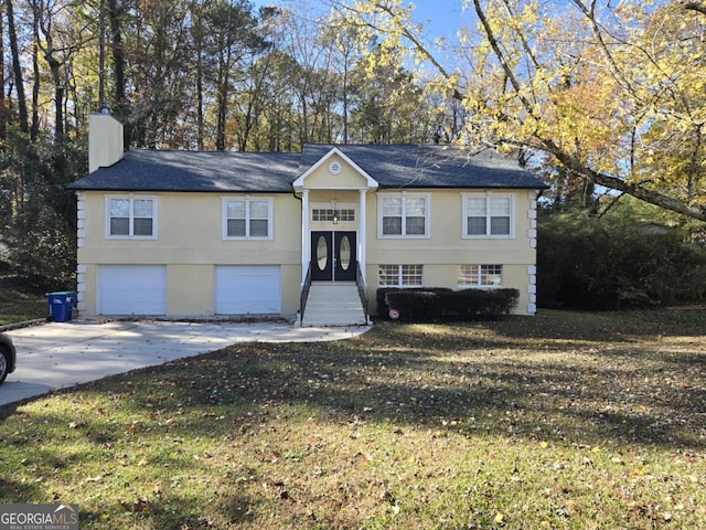 raised ranch featuring a garage and a front lawn