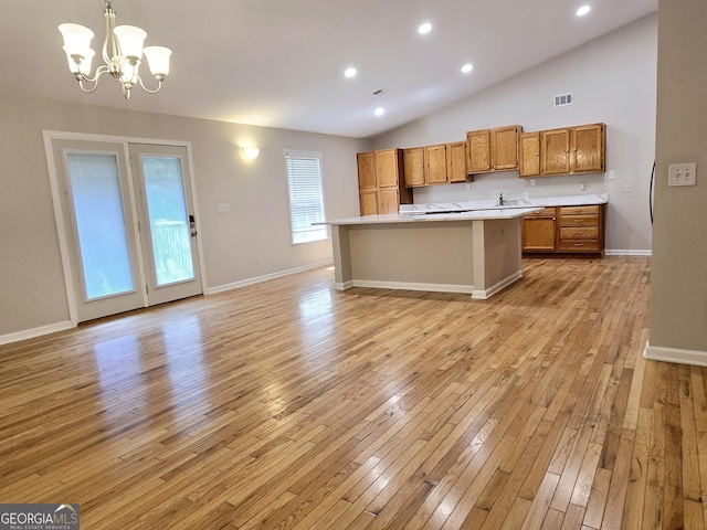 kitchen with pendant lighting, a notable chandelier, a kitchen island, vaulted ceiling, and light wood-type flooring