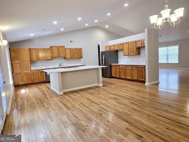 kitchen featuring pendant lighting, high vaulted ceiling, stainless steel refrigerator with ice dispenser, light hardwood / wood-style floors, and a kitchen island