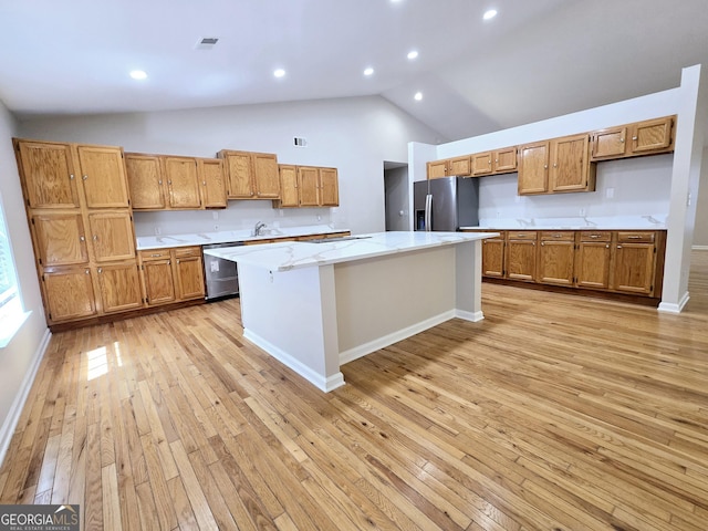 kitchen with a kitchen island, high vaulted ceiling, a kitchen bar, stainless steel appliances, and light wood-type flooring