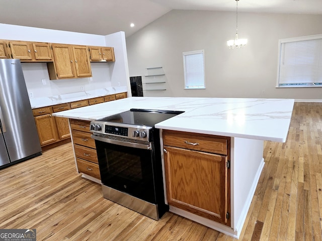 kitchen featuring vaulted ceiling, a kitchen island, appliances with stainless steel finishes, pendant lighting, and light wood-type flooring