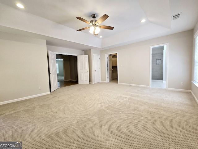 carpeted empty room featuring a raised ceiling and ceiling fan