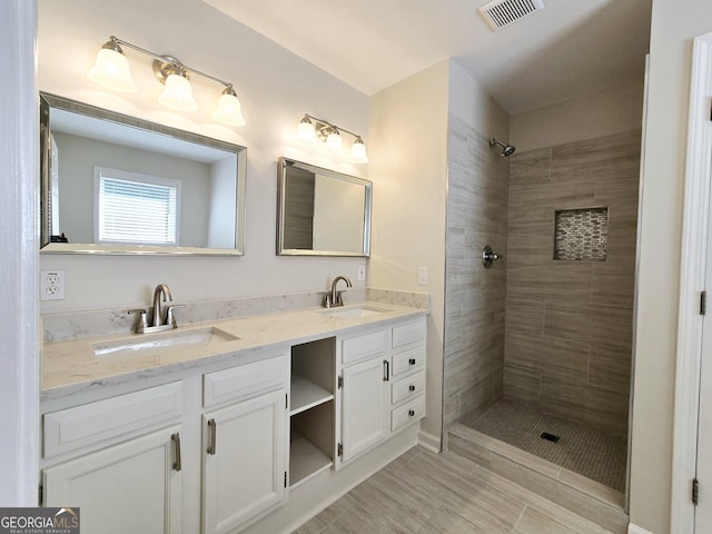 bathroom with vanity and tiled shower