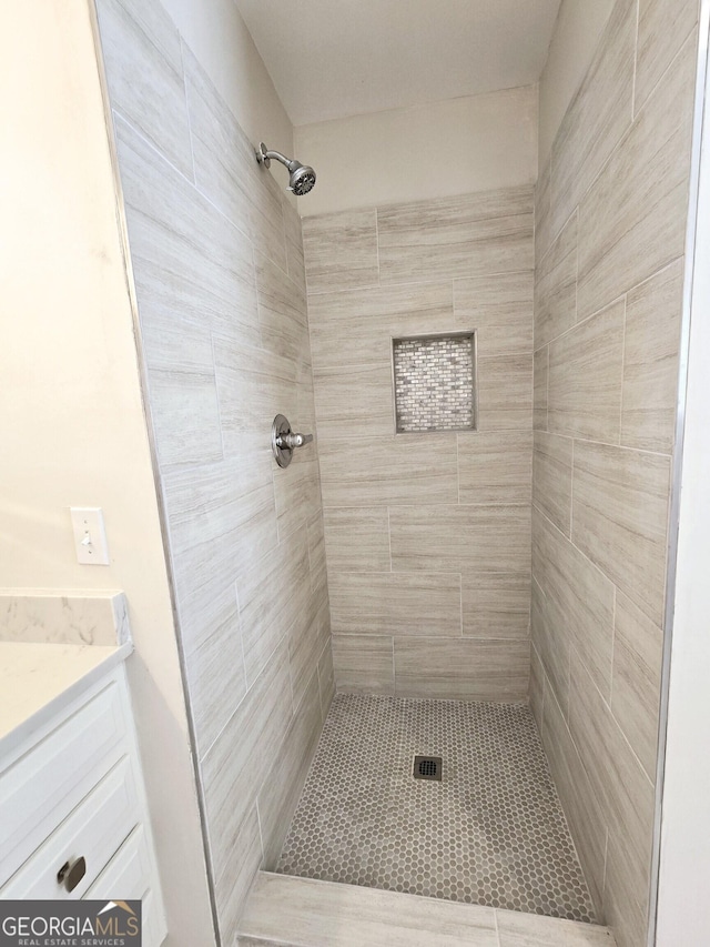 bathroom featuring tiled shower and vanity