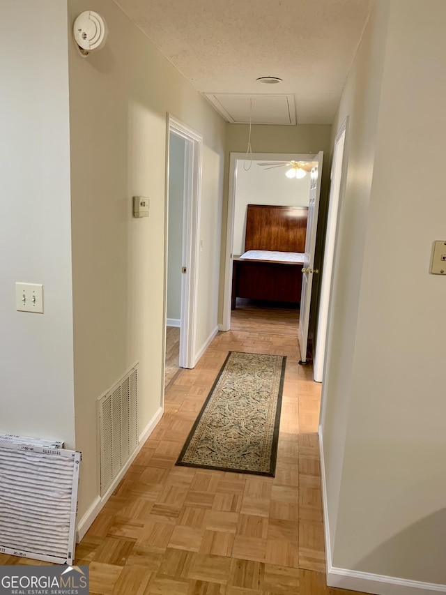 hallway with light parquet flooring and a textured ceiling