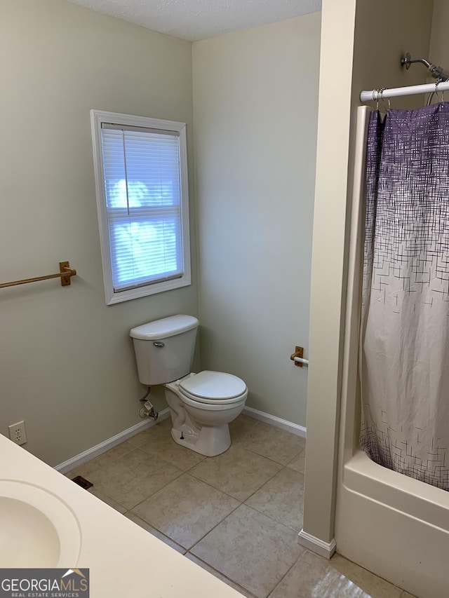 bathroom featuring shower / tub combo with curtain, tile patterned flooring, and toilet