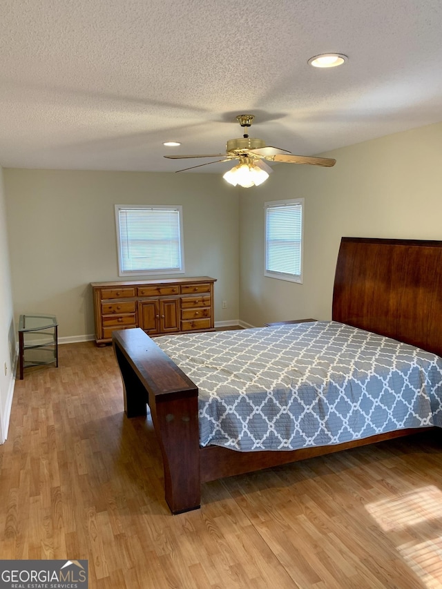 bedroom featuring ceiling fan, a textured ceiling, and light hardwood / wood-style flooring