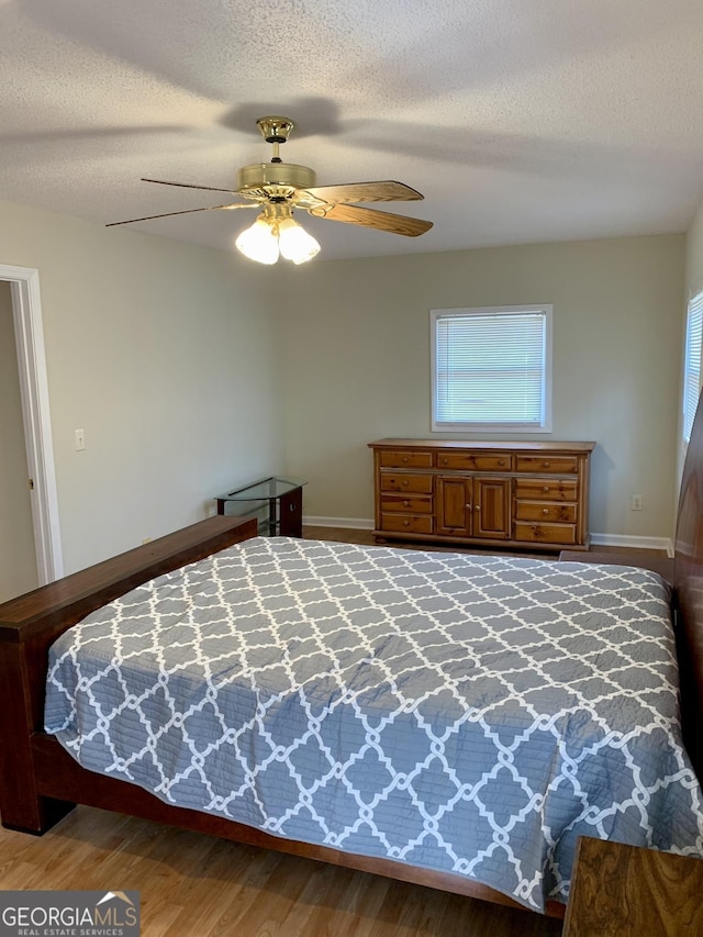 bedroom featuring ceiling fan, wood-type flooring, and a textured ceiling