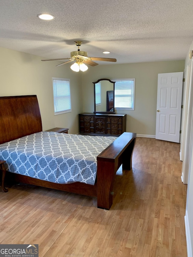 bedroom featuring ceiling fan, a textured ceiling, and light hardwood / wood-style floors