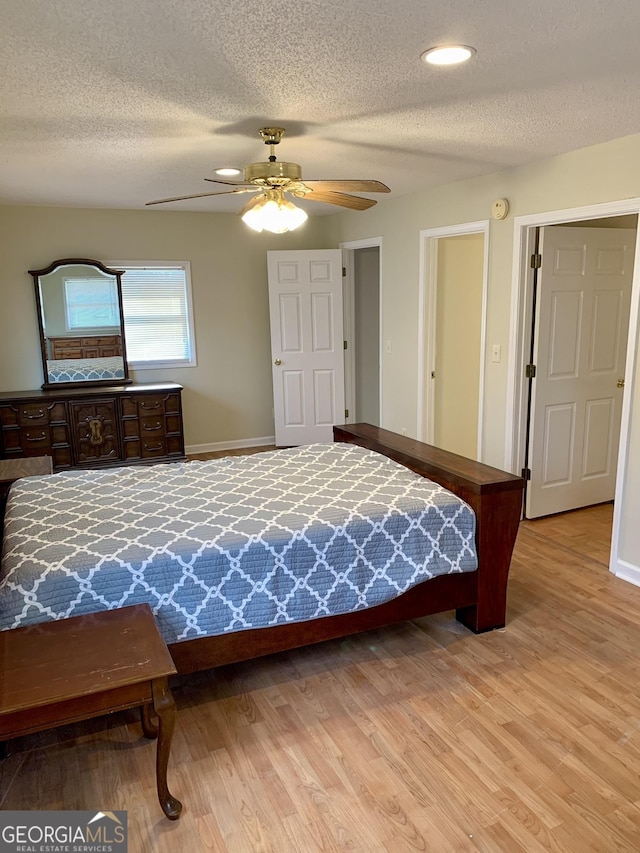 bedroom with ceiling fan, light hardwood / wood-style floors, and a textured ceiling