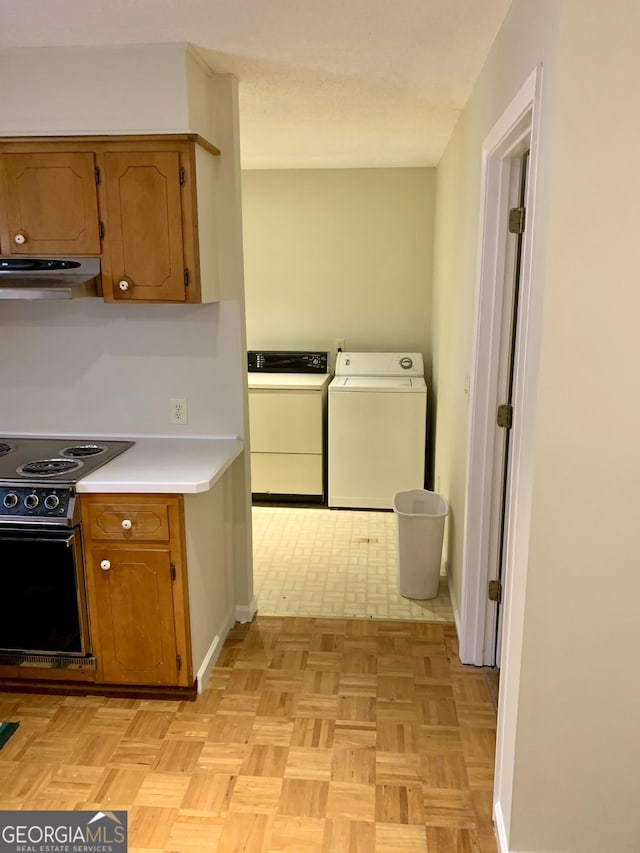 kitchen with electric range oven, washing machine and dryer, and light parquet floors