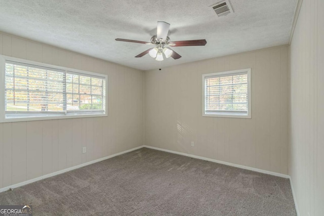 carpeted spare room featuring ceiling fan and a textured ceiling