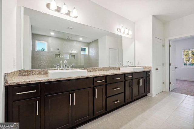 bathroom featuring a tile shower, vanity, and tile patterned floors