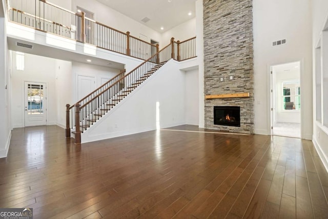 unfurnished living room featuring a fireplace, dark hardwood / wood-style flooring, and a high ceiling